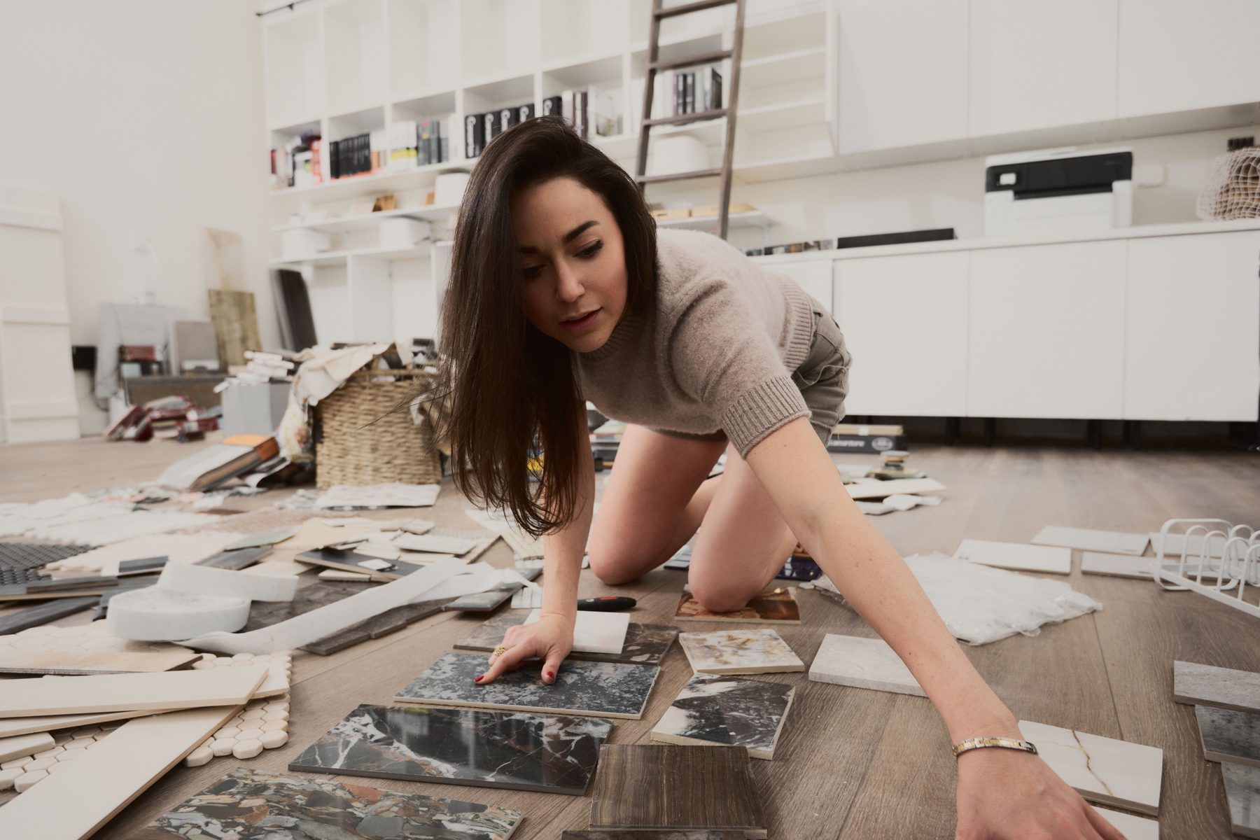 Shira Charles laying out stone and tile samples on the studio floor while making material selections
